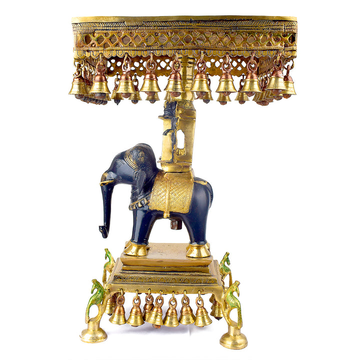 Large Brass Idol of 23 Inch Brass Chowki on Elephant with Hanging Bells. This 23 Inch Brass Chowki on Elephant with Hanging Bells is a stunning blend of artistry and tradition. Crafted from high-quality brass, the intricate detailing of the elephant and the delicately suspended bells add a touch of elegance to any space. 