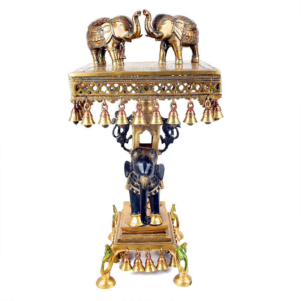 Large Brass Idol of 23 Inch Brass Chowki on Elephant with Hanging Bells. This 23 Inch Brass Chowki on Elephant with Hanging Bells is a stunning blend of artistry and tradition. Crafted from high-quality brass, the intricate detailing of the elephant and the delicately suspended bells add a touch of elegance to any space. 