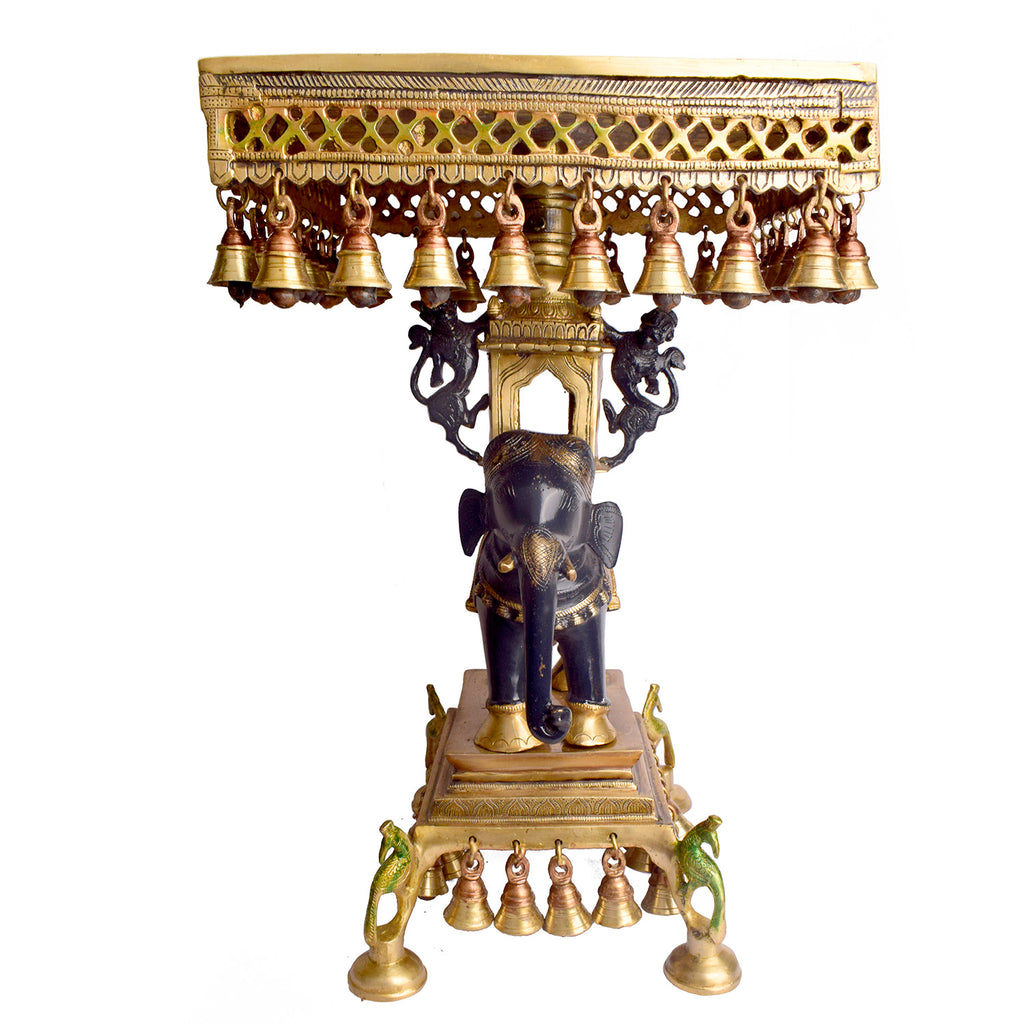 Large Brass Idol of 23 Inch Brass Chowki on Elephant with Hanging Bells. This 23 Inch Brass Chowki on Elephant with Hanging Bells is a stunning blend of artistry and tradition. Crafted from high-quality brass, the intricate detailing of the elephant and the delicately suspended bells add a touch of elegance to any space. 