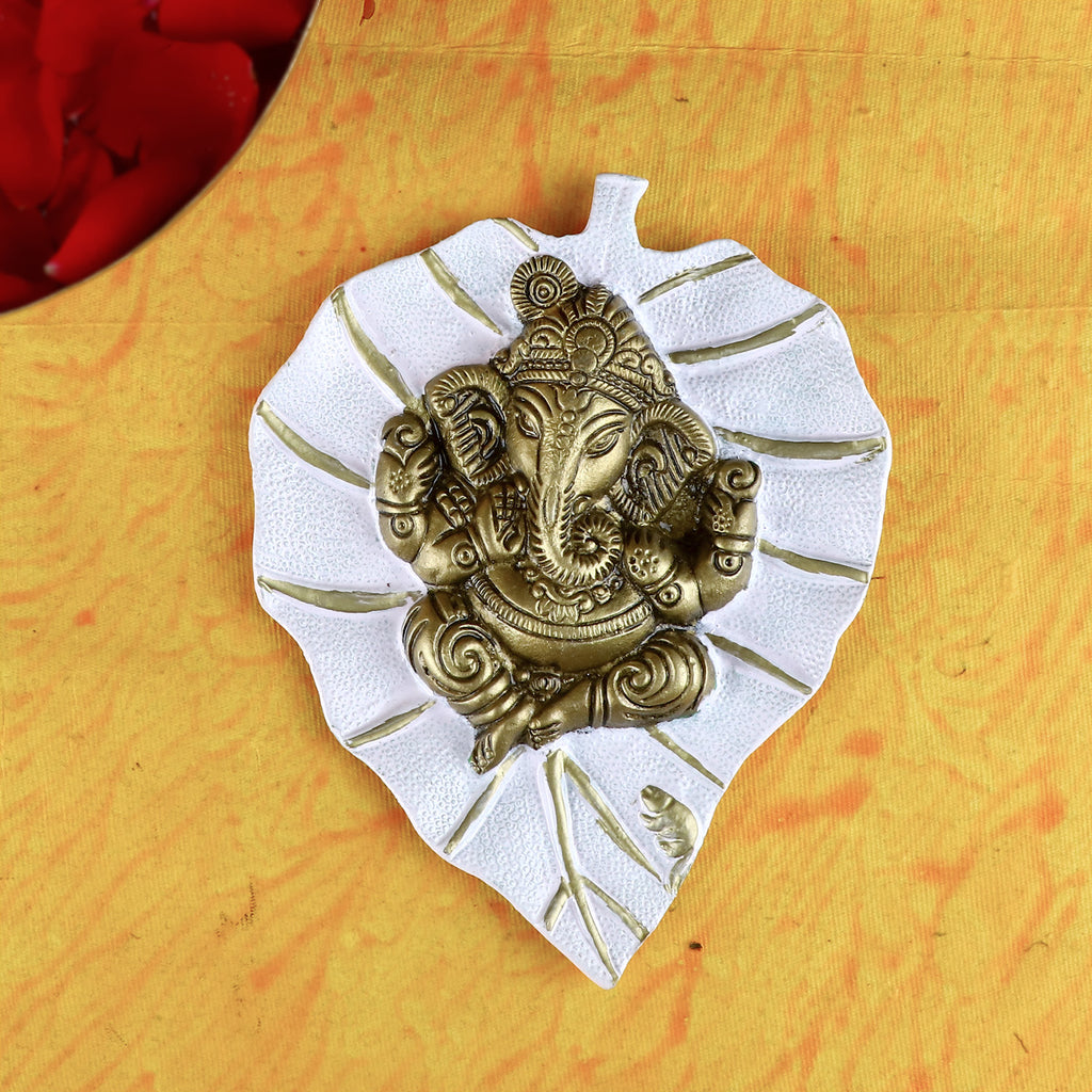 Elegant white leaf-shaped wall hanging featuring a serene idol of Lord Ganesh, ideal for enhancing spiritual ambiance and home decoration. India’s Largest Pooja Accessories Brand – www.satvikstore.in